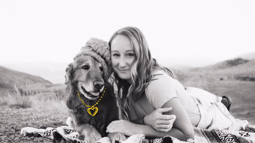 young woman and golden retriever outside on blanket looking at camera