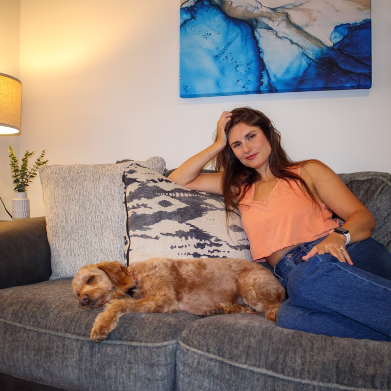 Morgan Sidwell and Sophie, her dog, on couch looking confidently at camera