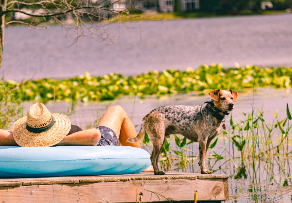 man laying on a float by the lake with his dog