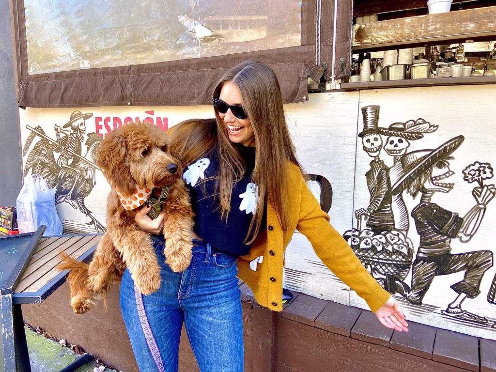 woman and dog standing outside in halloween clothing.
