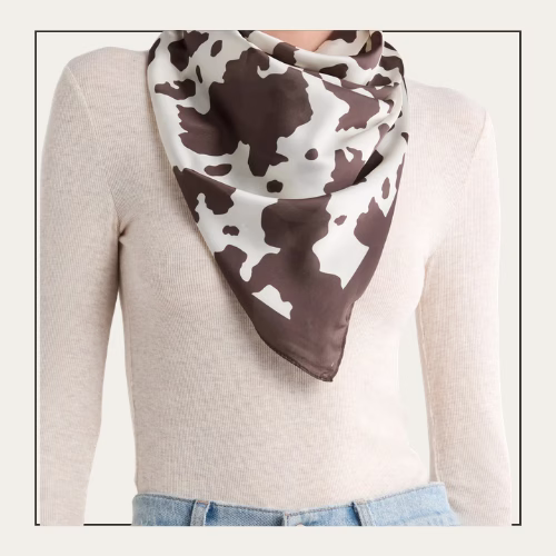 woman wearing a white sweater and a cow-print scarf