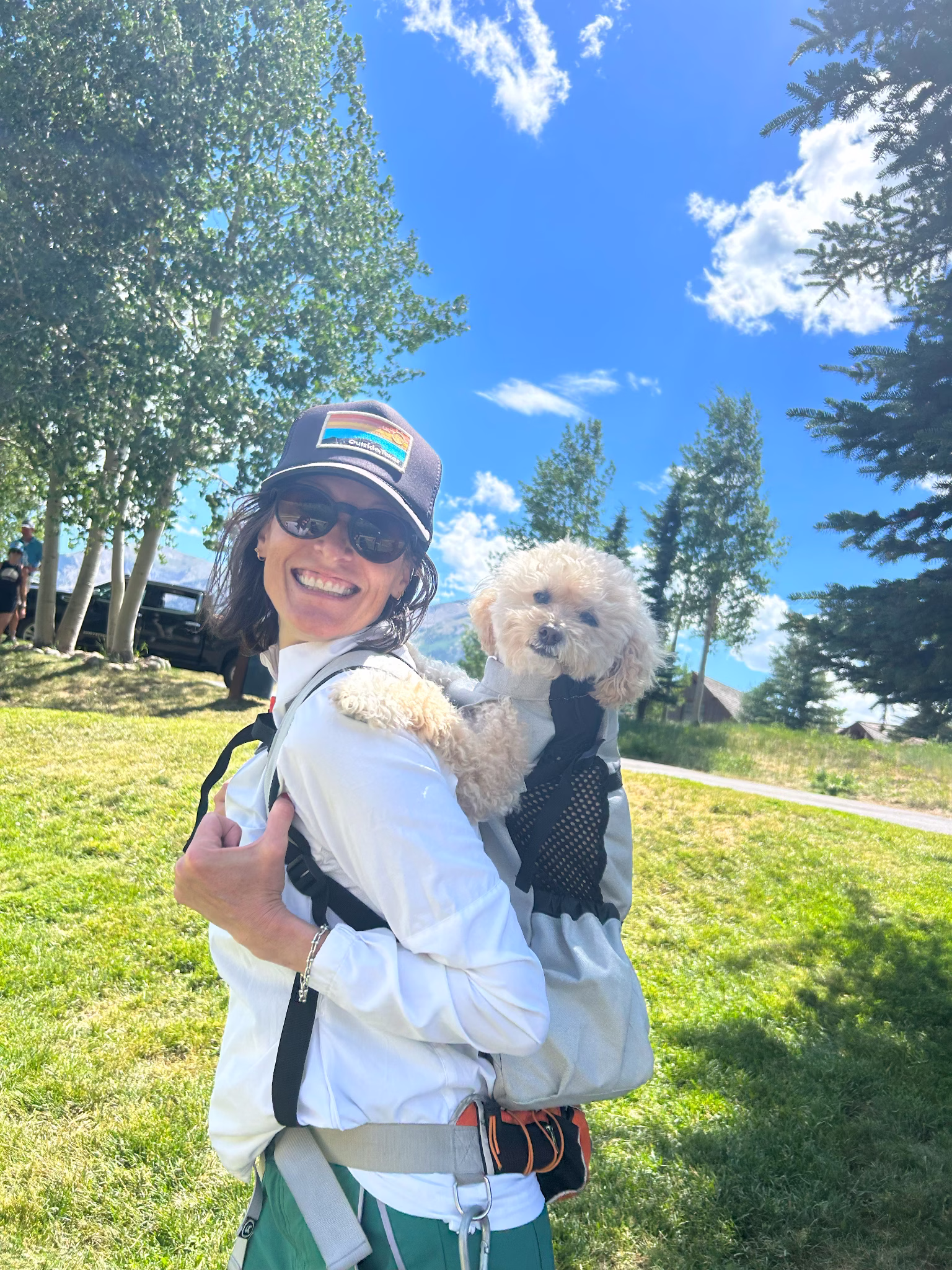 woman hiking with dog in backpack